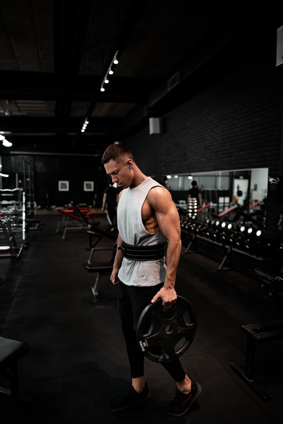 Athlete in a dark atelier gym carrying a plate